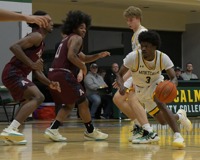 MCC men's basketball player Dorian Allen makes an aggressive drive to the hoop past two defenders during a home game.
