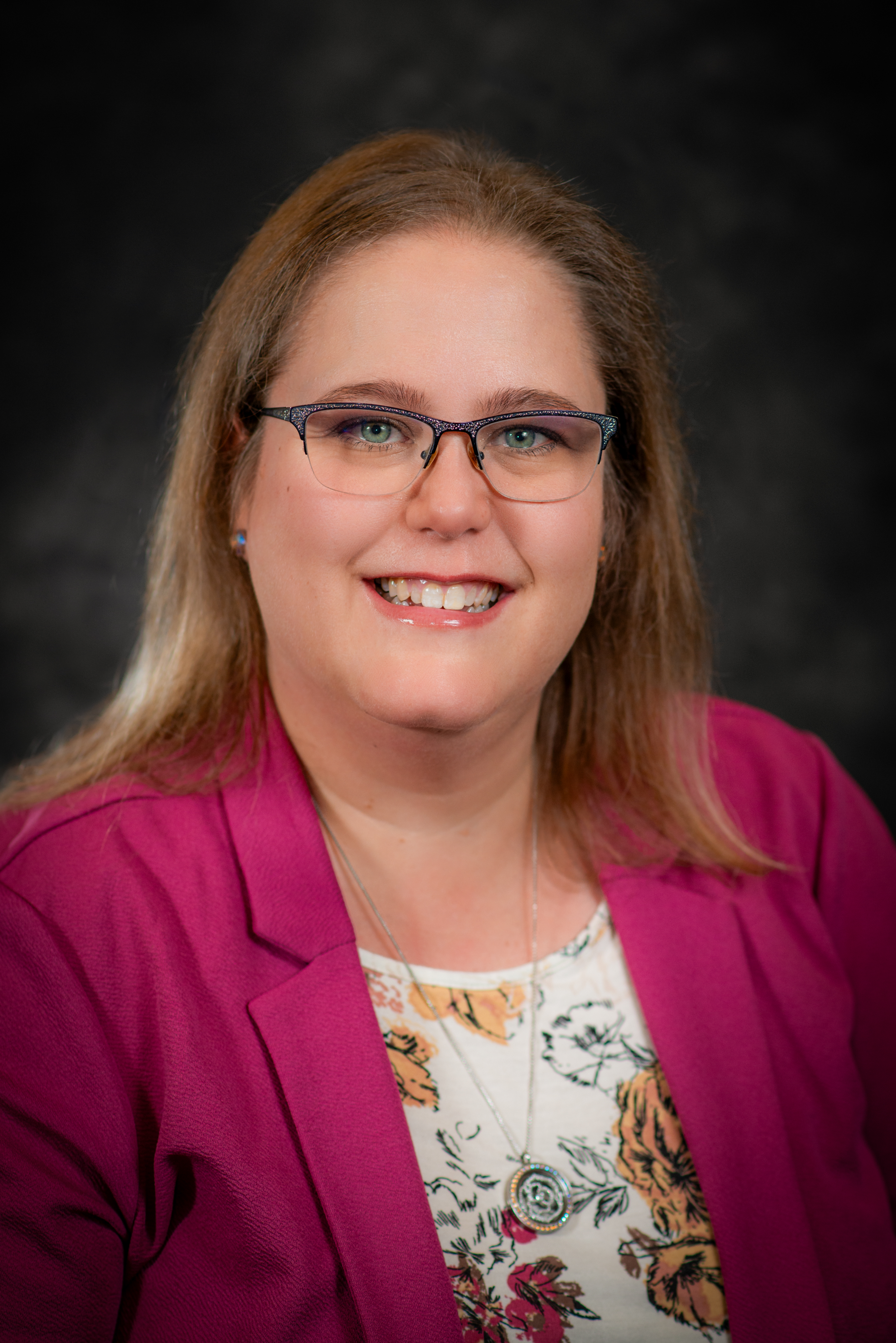 Professional photo of Jenniver VanderSlik wearing a pink blazer and white floral shirt.