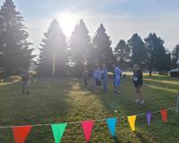 A group of six people to the right stand in a line while listening to instructions from a woman on the left.
