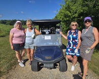 Four women standing around a golf cart at the 1st Annual Centurion Athletics Golf Outing.