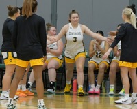MCC women's basketball player Emily Putnam emerges from the bench and extends her arms for high fives from her teammates.