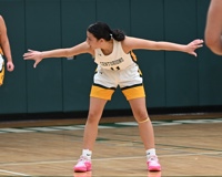 MCC women's basketball player Madi Longoria bends at her waist, looks to her right and stretches out her arms in a T-formation.