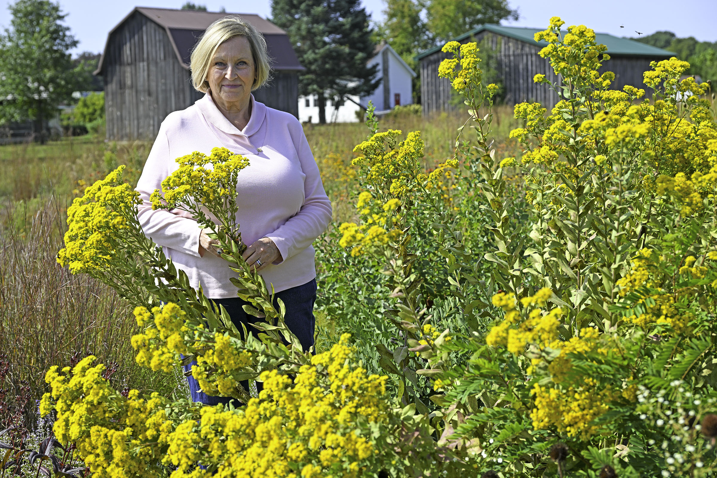 MCCF Scholarship creator, Sue Ann Aargaard standing outside near yellow flowers on the Sidney campus.