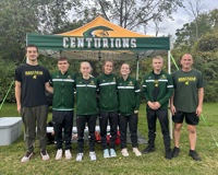 Six members of the MCC cross country team, and their head coach, pose for a photo in front of their team tent.