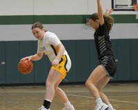 MCC women's basketball player Emily Putnam dribbles with her back to her opponent, who has her arms straight up in the air to defend.
