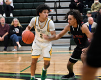 MCC basketball player Taylen Carver dribbles laterally on the court with his right hand while his opponent has their right hand near his torso.