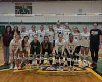 Members of the MCC volleyball team, along with their coaches, pose for a group photo on their home court.