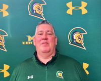 MCC women's basketball head coach Scott Pedigo poses for a photo while standing in front of an MCC athletics backdrop.