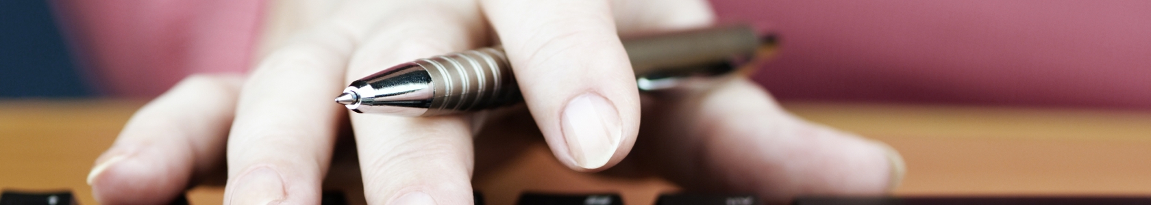 Hand with pen and keyboard